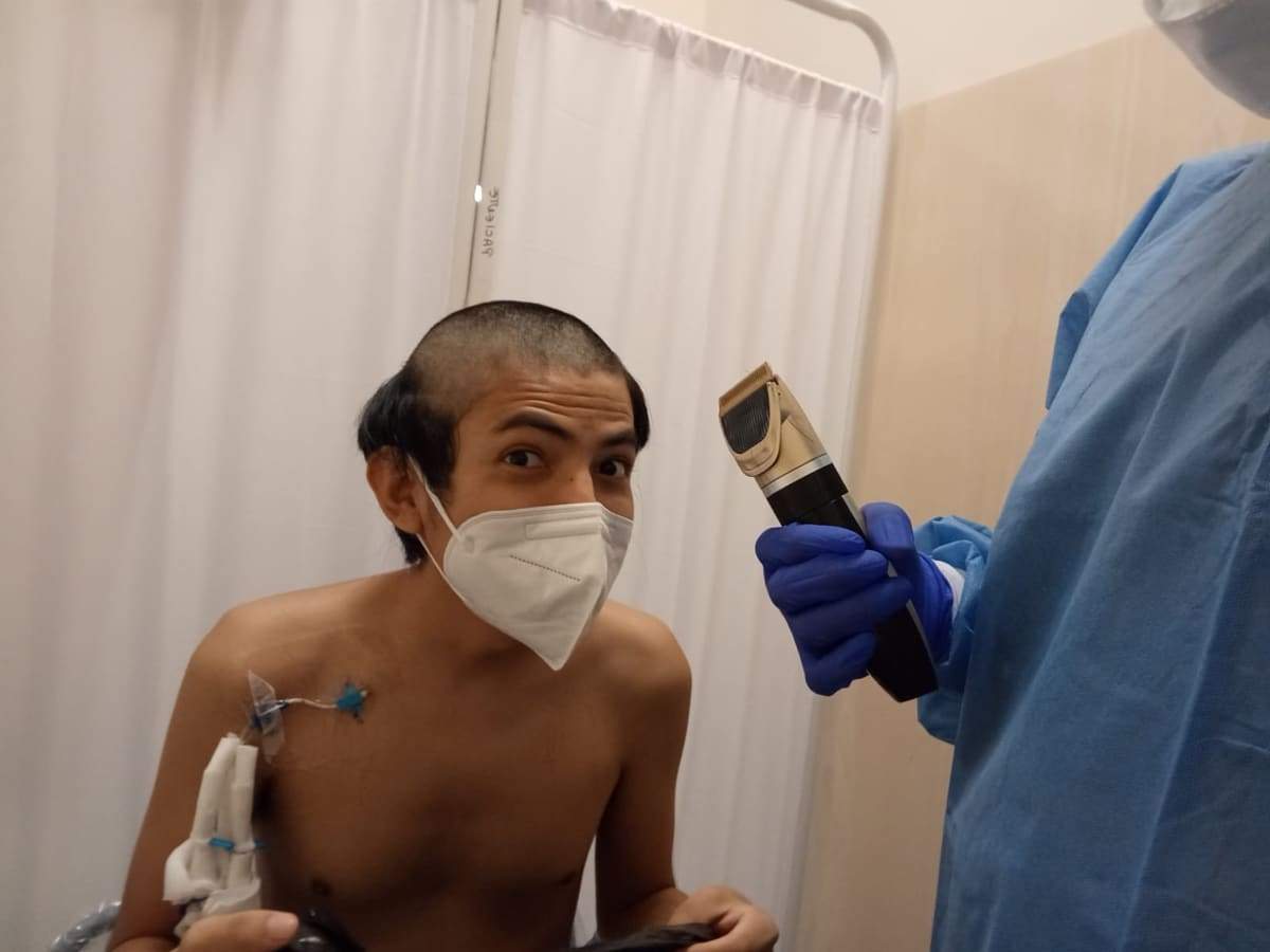 Joseph con mascarilla mientras le rapan la cabeza por la quimioterapia