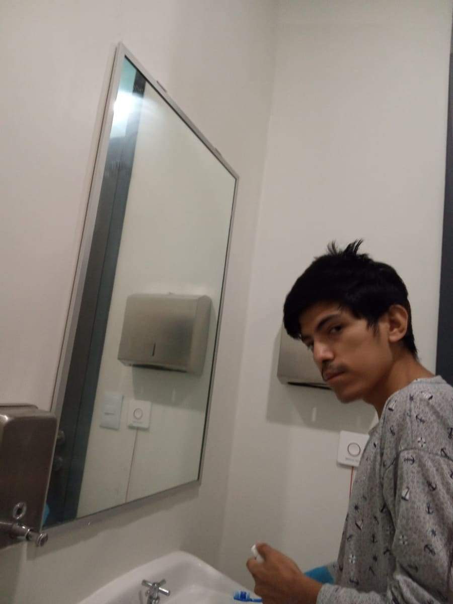 Joseph pálido y agotado frente al espejo de un baño del hospital