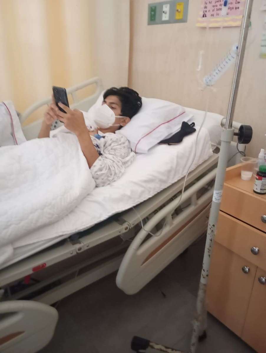 Joseph acostado en la cama del hospital usando el celular