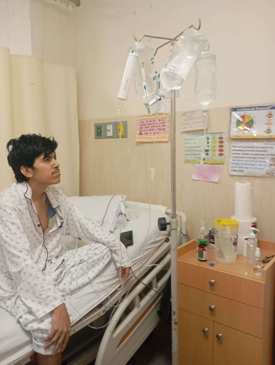 Joseph sentado al borde de la cama junto al poste de suero