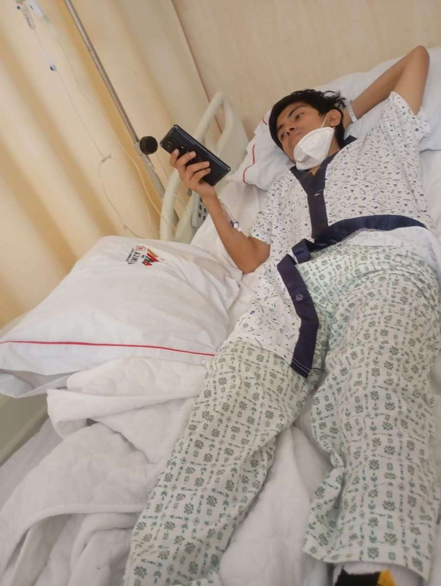 Joseph acostado en la cama de hospital con el celular